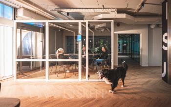 Modern kantoorpand aan Rietbaan 2-12 in Capelle aan den IJssel met een vergaderruimte waar drie personen zitten te overleggen. Gezellige sfeer, ideaal voor kantoorruimte huren.