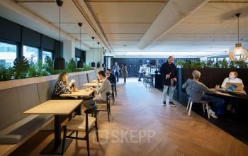Moderne kantoorlounge op Rietbaan 2-12 in Capelle aan den IJssel, met werknemers die samenwerken en vergaderen in een open en lichte ruimte. Ideaal om kantoorruimte te huren voor dynamische teams.