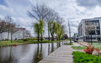 Een exterieur van het kantoorpand op Rietbaan 2-12, Capelle aan den IJssel, met een wandelpad langs een waterpartij. Kantoorruimte huren in een aantrekkelijke omgeving.
