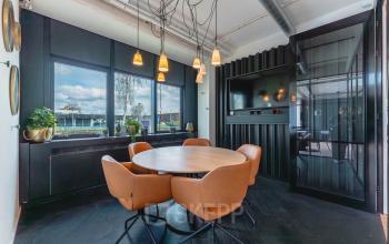 Moderne conferentieruimte met ronde houten tafel en zes leren stoelen bij Rietbaan 2-12, Capelle aan den IJssel, geschikt voor kantoorruimte huren.