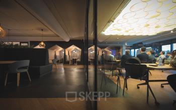 Binnen in het kantoorpand Rietbaan 2-12, Capelle aan den IJssel zijn mensen aan het vergaderen in een stijlvol ingerichte ruimte. Ideaal voor kantoorruimte huren met moderne voorzieningen.