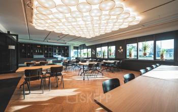 Ruime en moderne werkruimte in Capelle aan den IJssel met stijlvolle tafels en ramen die veel natuurlijk licht binnenlaten. Perfect voor wie kantoorruimte wil huren en een professionele omgeving zoekt.