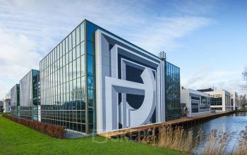 Moderne kantoorpand Rietbaan 2-12 in Capelle aan den IJssel, met opvallende architectuur en glazen gevels, omgeven door water en groen. Ideale locatie om kantoorruimte te huren.