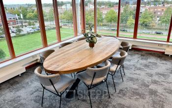 Vergaderruimte in een kantoorpand aan de Fascinatio Boulevard 562, Capelle aan den IJssel, met een grote houten tafel en ramen met uitzicht op groen.