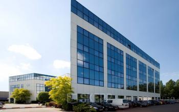 Exterieur van modern kantoorpand op Rietbaan 40-42 in Capelle aan den IJssel met ruime parkeerfaciliteiten. Grote glazen gevels reflecteren de blauwe lucht, ideaal om kantoorruimte te huren.
