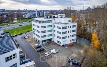 Exterieur van het kantoorpand op Rhijnspoor 209-263, Capelle aan den IJssel, omgeven door parkeerplaatsen en omringende stedelijke omgeving.