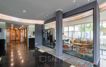 Moderne ontvangsthal in kantoorpand op Rhijnspoor 209-263, Capelle aan den IJssel, met comfortabele zithoek en glazen scheidingswanden voor een open en lichte sfeer.