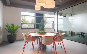 Kantoorruimte huren aan de Fascinatio Boulevard 522 in Capelle aan den IJssel, met een moderne vergadertafel en kleurrijke stoelen, omringd door glazen wanden en natuurlijke lichtinval.