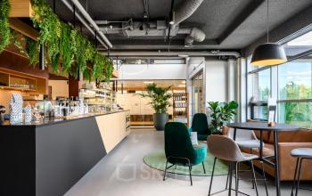 Moderne kantoorruimte huren in Capelle aan den IJssel met stijlvolle inrichting, inclusief groene planten en zitgelegenheid. Licht interieur met veel ramen en een sfeervolle ambiance.