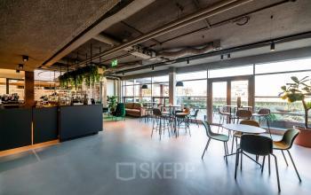 Interieur van een modern kantoorpand met een lichte en ruime lounge op de Fascinatio Boulevard 522 in Capelle aan den IJssel, ingericht met tafels en stoelen voor informele vergaderingen.