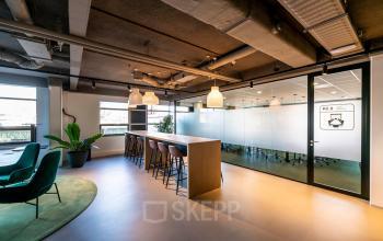 Kantoorruimte huren aan de Fascinatio Boulevard 522 in Capelle aan den IJssel, met moderne inrichting, een lange tafel met barkrukken, hanglampen en een vergaderruimte achter glas.