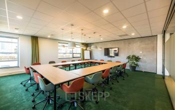 Vergaderruimte in kantoorpand Fascinatio Boulevard 522, Capelle aan den IJssel, met moderne, kleurrijke stoelen en grote houten tafels. Perfecte locatie voor kantoorruimte huren.