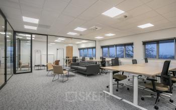 Moderne kantoorruimte met glazen wanden en uitzicht op Rivium Quadrant 75, Capelle aan den IJssel. Meerdere werkplekken met bureaus en comfortabele stoelen. Ruimte geschikt voor kantoorgebruik.