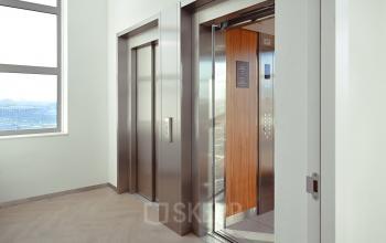 Lift en gang in kantoorpand aan Rivium Quadrant 75, Capelle aan den IJssel, met zicht op moderne liften. Geschikt voor bedrijven die kantoorruimte willen huren.