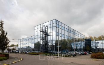 Modern kantoorpand met spiegelende gevel aan de Essebaan 63 in Capelle aan den IJssel, met parkeergelegenheid op de voorgrond.