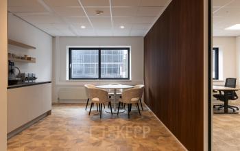 Kantoorruimte huren op Essebaan 63, Capelle aan den IJssel, met een moderne inrichting. De ruimte bevat een tafel met stoelen en een kitchenette.