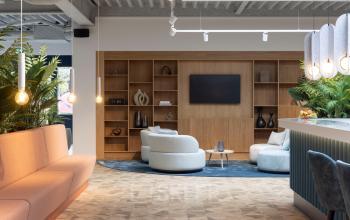 Moderne lobby met zachte banken, houten wandrekken en planten, ideaal voor kantoorruimte huren in kantoorpand aan Essebaan 63, Capelle aan den IJssel.