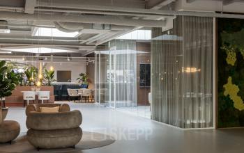 Moderne en stijlvolle kantoorruimte in Capelle aan den IJssel met comfortabele zitplaatsen, glazen wanden en groene accenten. Ideaal voor het huren van een inspirerende werkplek.