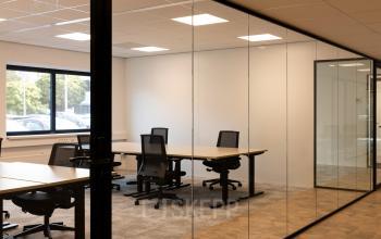 Kantoorruimte met glazen wanden, voorzien van bureaus en stoelen, gelegen op Essebaan 63 in Capelle aan den IJssel. Deze stijlvolle kantooromgeving is klaar voor verhuur.