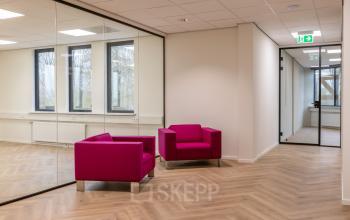 Een lichte kantoorruimte op Vlierbaan 20, Capelle aan den IJssel, met glazen wanden en twee roze fauteuils, ideaal voor het huren van een stijlvol kantoorpand.