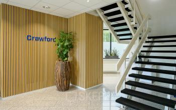 In de kantoorruimte op Vlierbaan 20 in Capelle aan den IJssel bevindt zich een trap, een houten wand en een grote plant op een stenen vloer.