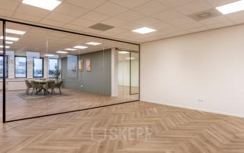 Moderne kantoorruimte aan de Vlierbaan 20, Capelle aan den IJssel, met houten vloer en glazen wand. Ideaal voor bedrijven om kantoor te huren. Grote ramen zorgen voor veel natuurlijk licht.