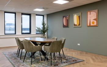 Kantoorruimte op Vlierbaan 20, Capelle aan den IJssel met een stijlvolle vergadertafel, zes stoelen en kunstwerken aan de muur.