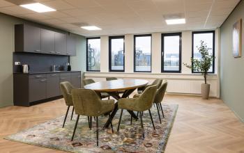 Moderne kantoorruimte met ronde tafel en zes stoelen, vlakbij het raam, op Vlierbaan 20. Voorzien van een kitchenette. Ideaal voor wie kantoorruimte wil huren in Capelle aan den IJssel.