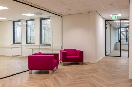 Een lichte kantoorruimte op Vlierbaan 20, Capelle aan den IJssel, met glazen wanden en twee roze fauteuils, ideaal voor het huren van een stijlvol kantoorpand.
