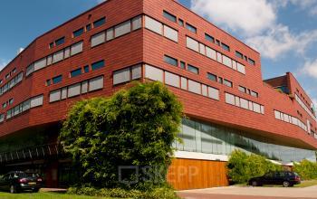 Roodbruin kantoorpand aan de Multatulilaan 12 in Culemborg, met moderne architectuur en parkeergelegenheid voor het gebouw. Ideaal voor bedrijven op zoek naar een representatieve locatie om een kantoor te huren.