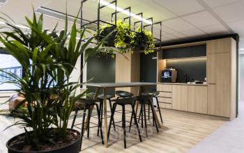 Moderne kantoorpand op Rijnzathe 6 in De Meern met stijlvolle inrichting en groene accenten. Ideale mogelijkheid voor kantoorruimte huren met faciliteiten zoals hoge tafels en relaxte zithoek.