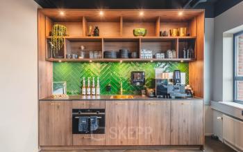 Stijlvolle pantry met houten kasten en groene tegelwand, ideale kantoorruimte huren in kantoorpand Rijnzathe 12, De Meern.