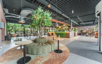 Moderne kantoorruimte op Rijnzathe 12, De Meern, met groene accenten en een uitnodigende inrichting voor vergaderingen of flexwerken. Grote ramen zorgen voor veel natuurlijk licht.