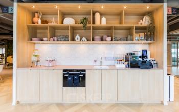 Stijlvolle pantry met houten kasten en moderne apparatuur in een kantoorpand op Rijnzathe 12, De Meern. Ideaal voor een pauze tijdens het kantoorwerk. Overweeg deze ruimte te huren.