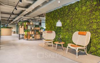 Moderne kantoorruimte aan Rijnzathe 12 in De Meern met een rustgevende groene wand, comfortabele zitplaatsen en stijlvolle inrichting. Perfect voor wie op zoek is naar een duurzame en inspirerende werkplek.