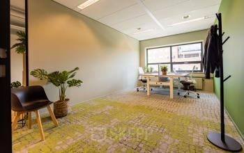 Kantoorruimte huren in een modern ingericht kantoorpand op Rijnzathe 12, De Meern. De lichte werkruimte heeft grote ramen en twee bureaus met stoelen, met planten die een frisse uitstraling geven.
