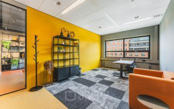 Kantoorruimte huren in De Meern op Rijnzathe 12 met kleurrijke muren en grote ramen. Het kantoor is ingericht met een bureau, stoel en kast. Modern en uitnodigend voor zakelijke activiteiten.