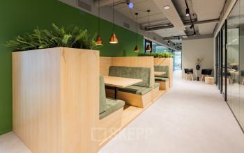Moderne zithoek met houten en groene elementen in een kantoorruimte aan Rijnzathe 12, De Meern. Ideaal voor informele ontmoetingen binnen het kantoorpand wat je kunt huren.