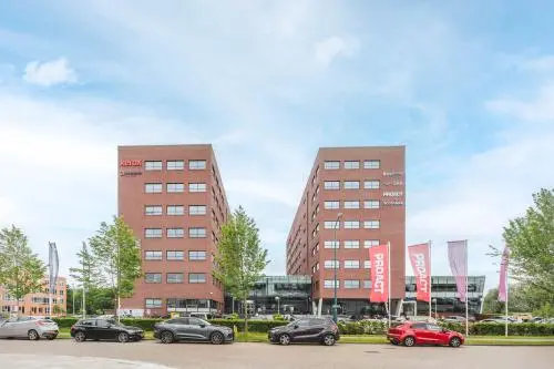 Twee moderne bakstenen kantoorgebouwen op Rijnzathe 12, De Meern, met voorzijde geparkeerde auto's en vlaggen. Ideaal voor kantoorruimte huren met goede zichtlocatie en toegang.
