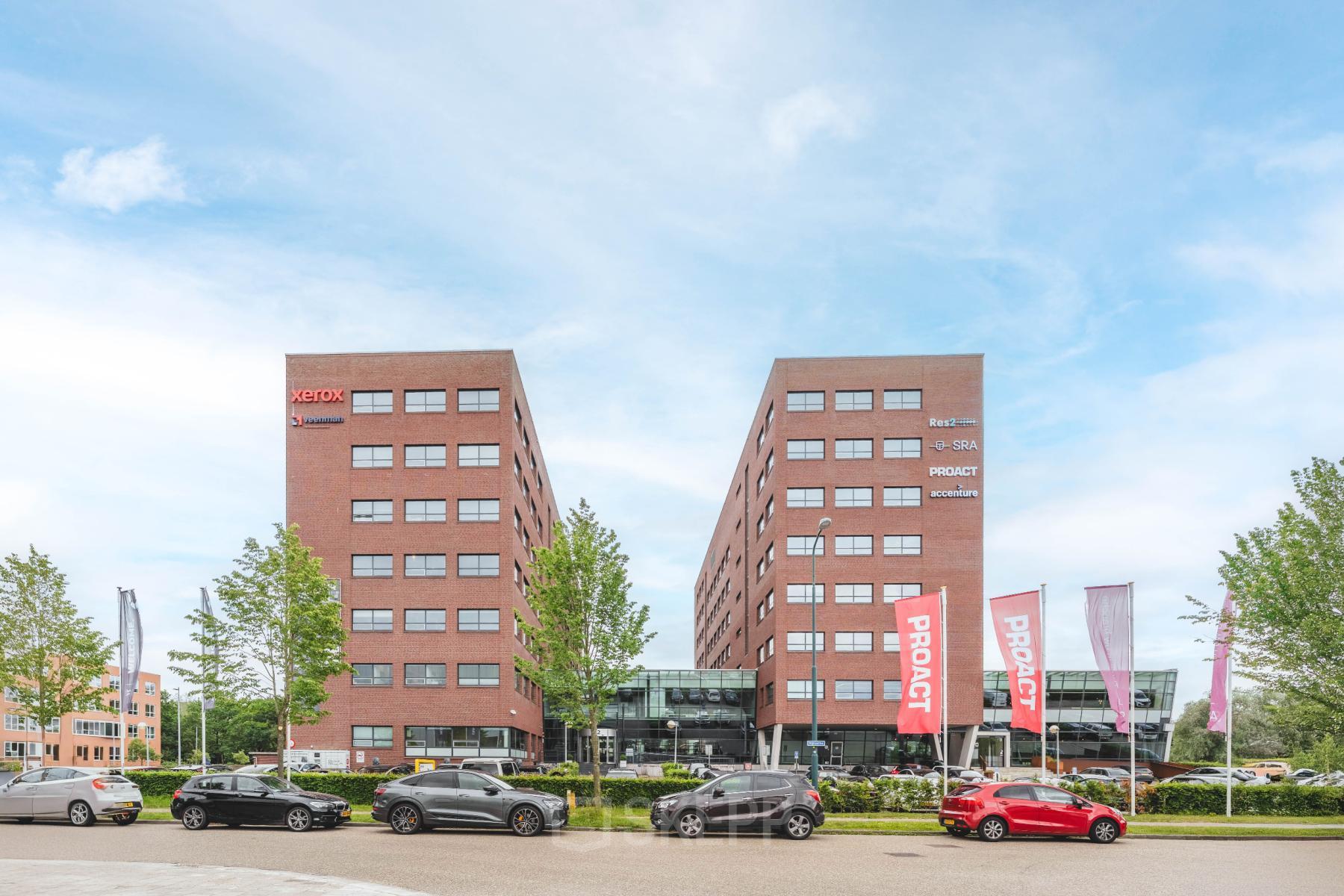 Twee moderne bakstenen kantoorgebouwen op Rijnzathe 12, De Meern, met voorzijde geparkeerde auto's en vlaggen. Ideaal voor kantoorruimte huren met goede zichtlocatie en toegang.