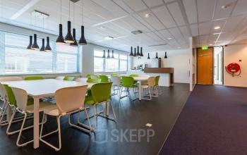 Kantoorruimte huren op Delftechpark 17-19 in Delft. Moderne werkruimte met veel lichtinval, zithoeken met groene stoelen en een minimalistisch interieurontwerp. Ideaal voor diverse zakelijke activiteiten.