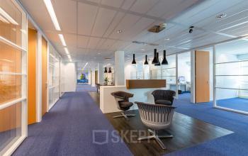 Moderne kantoorruimte huren op Delftechpark 17-19, Delft met stijlvolle afwerking, blauwe vloerbedekking, glazen wanden en een ontvangstruimte met stoelen en hangende lampen.