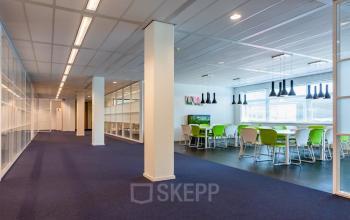 Moderne kantoorruimte met groene stoelen en veel natuurlijk licht op Delftechpark 17-19, Delft. Grote glazen wanden scheiden verschillende werkruimtes.