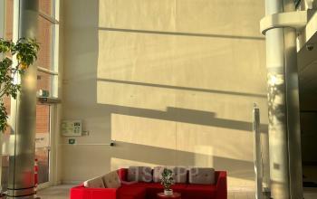 Ruime entree met een rode bank en glazen gevel, ideaal voor bedrijven die kantoorruimte willen huren op Olof Palmestraat 10 in Delft.