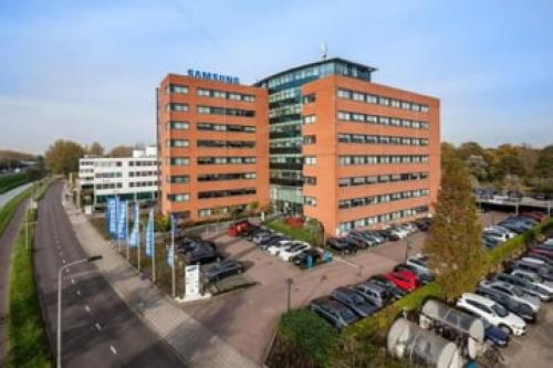 Buitenaanzicht van het kantoorpand aan de Olof Palmerstraat 10 in Delft, met meerdere verdiepingen en parkeerplaatsen, ideaal voor kantoorruimte huren.