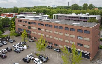 Buitenaanzicht van een kantoorpand op Delftechpark 9, Delft. Verschillende auto's geparkeerd op de parkeerplaats rondom het gebouw. Ideale plek voor kantoorruimte huren in Delft.