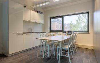 Kantoorruimte met een tafel en zes stoelen bij Delftechpark 9, Delft. Houten vloer en groot raam met uitzicht. Ideaal voor vergaderingen of als gezamenlijke werkplek. Geschikt voor het huren van een kantoorpand.