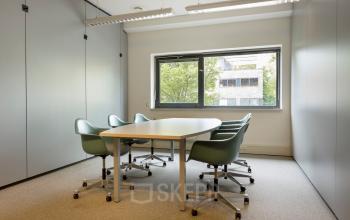 Compacte kantoorruimte huren op Delftechpark 9 in Delft, voorzien van een vergadertafel en stoelen met uitzicht op groen. Ideaal voor kleine bijeenkomsten in een rustige omgeving.
