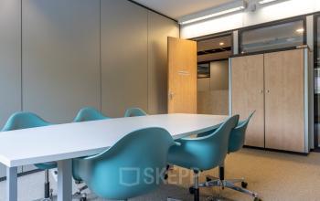 Vergaderruimte in kantoorpand op Delftechpark 9, Delft met lange tafel, blauwe stoelen en een kast. Perfect voor kantoorruimte huren die inspirerend en functioneel is.