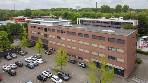 Buitenaanzicht van een kantoorpand op Delftechpark 9, Delft. Verschillende auto's geparkeerd op de parkeerplaats rondom het gebouw. Ideale plek voor kantoorruimte huren in Delft.